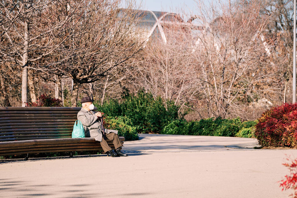 Madrid, Spain - 13 january 2022. Senior man enjoying the sun sitting on park bench in Madrid Rio. Retirement concept - Fotografie, Obrázek