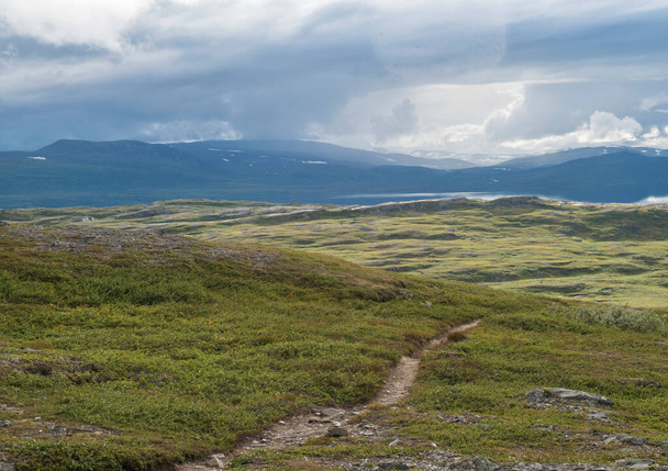 Paysage de Laponie au lac Virihaure avec rivière sinueuse, montagnes verdoyantes, bouleaux et plaine avec de gros rochers. Suède été nuageux, nature sauvage, Padjelantaleden randonnée. - Photo, image