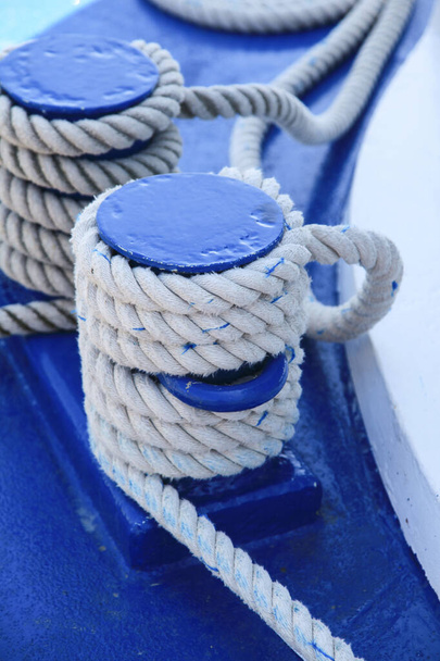 White ropes tied to blue wooden poles on deck of a sailing boat - Foto, afbeelding