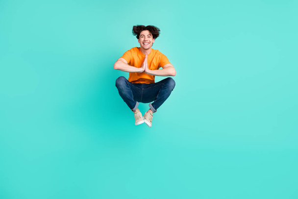 Full length photo of funky brown hair millennial guy jump wear t-shirt jeans sneakers isolated on blue background. - Foto, imagen