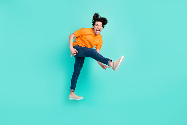 Full length photo of cool brown hair millennial guy jump yell wear t-shirt jeans sneakers isolated on blue background. - Φωτογραφία, εικόνα