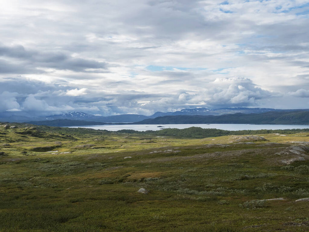 Paysage de Laponie au lac Virihaure avec rivière sinueuse, montagnes verdoyantes, bouleaux et plaine avec de gros rochers. Suède été nuageux, nature sauvage, Padjelantaleden randonnée. - Photo, image