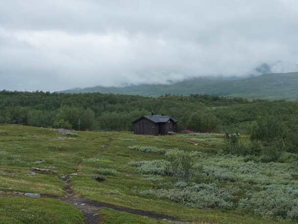 Sami köyü Staloluokta Virihaure Gölü 'nde evleri, kulübeleri, dağları ve huş ağaçlarıyla. Padjelantaleden yürüyüş parkurunda yaz havası ve sisli bir gün. İsveç Laponya manzarası - Fotoğraf, Görsel