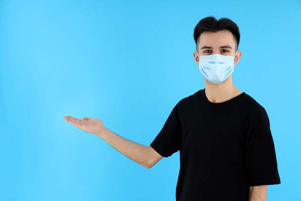 Joven hombre en máscara médica sobre fondo azul - Foto, imagen