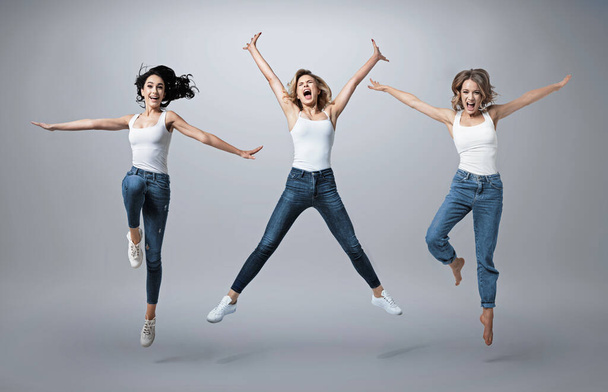 Group of beautiful  young women wearing white shirt and denim jeans having fun - Fotó, kép