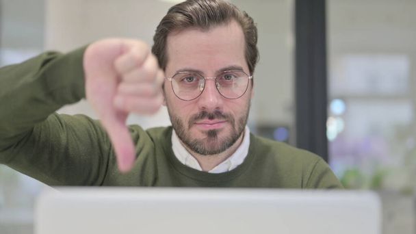 Close-up van jonge zakenman met laptop toont duimen naar beneden - Foto, afbeelding