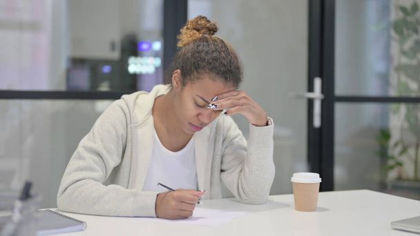 African Woman having Disappointment while Writing on Pape - 写真・画像
