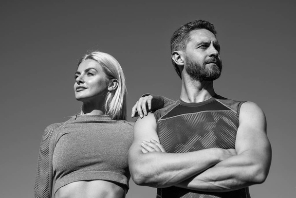 με αυτοπεποίθηση αθλητικό ζευγάρι σε αθλητικά ρούχα χαλαρώστε στο φόντο του ουρανού, γυμναστήριο - Φωτογραφία, εικόνα