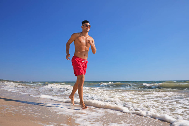 Jóképű férfi vonzó test fut a strandon - Fotó, kép