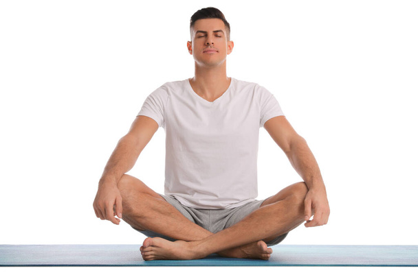 Handsome man meditating on yoga mat against white background - Photo, image