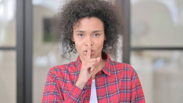 Retrato de mujer africana poniendo dedo en los labios, silencio - Foto, imagen