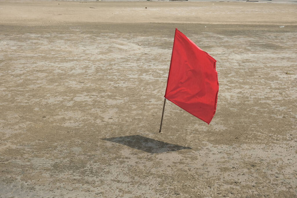 Selective focus and close up picture picture of waving red flag at the beach with strong water wave insight. In Malaysia, monsoon season is not the best time to go to the beach. - Photo, Image