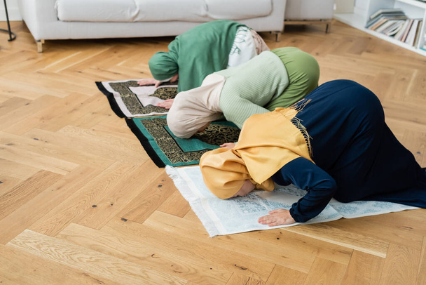 Multiethnische Frauen und Mädchen in Hijabs beugen sich zu Hause auf Lumpen  - Foto, Bild