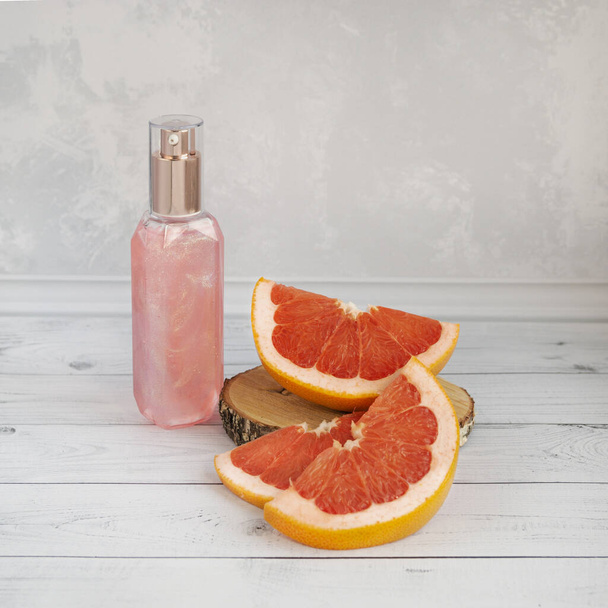 Grapefruit slices and a bottle of pink shower gel. Natural cosmetics concept. - Valokuva, kuva