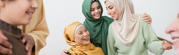 Uśmiechnięta międzyrasowa muzułmańska rodzina przytulająca się w domu, sztandar  - Zdjęcie, obraz