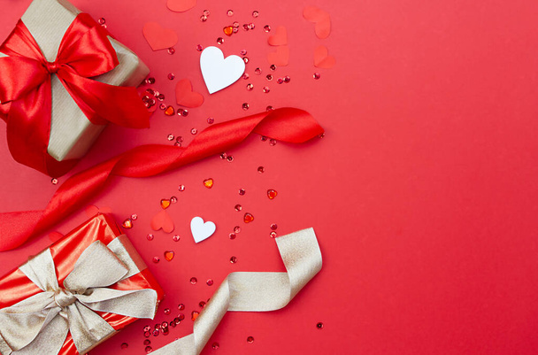 Kreative Komposition mit Geschenken, Bändern und Herzen auf rotem Hintergrund. - Foto, Bild