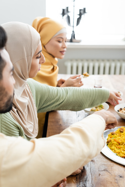 young muslim woman having dinner with blurred multiethnic family - Фото, изображение