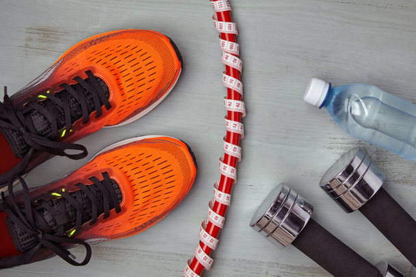 Orange sports sneakers, a gymnastic hoop wrapped in a measuring tape with a meter, - Zdjęcie, obraz