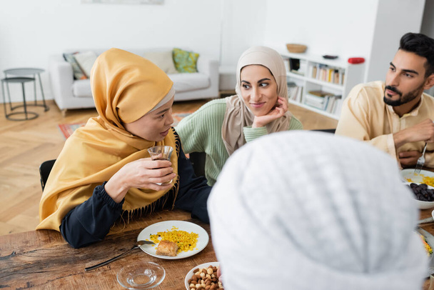 Asiatin mittleren Alters spricht während des Abendessens zu Hause mit muslimischer Familie - Foto, Bild