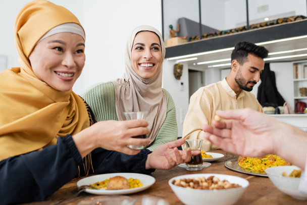 gai asiatique femme tenant tasse de thé pendant dîner avec musulman famille - Photo, image