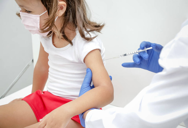 Dziecko szczepione przeciw zakażeniu wirusem covid 19 wraca do szkoły medycznej z niebieską rękawiczką i strzykawką.. - Zdjęcie, obraz
