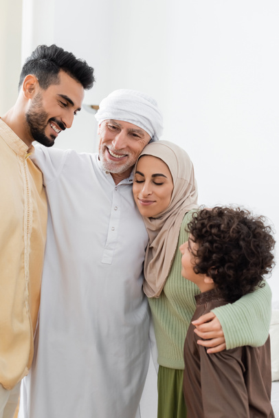cheerful multiethnic muslim family embracing at home - Foto, imagen