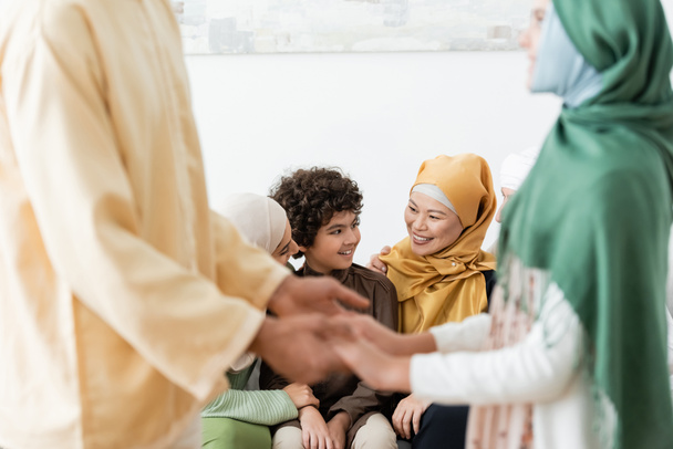 blurred man holding hands of daughter near happy multiethnic muslim family - 写真・画像