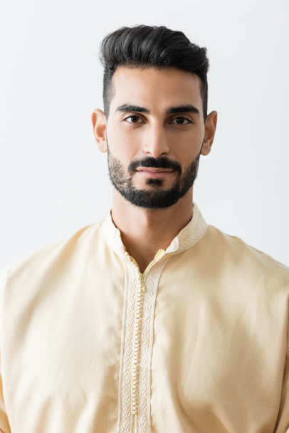 young bearded muslim man in traditional clothes looking at camera isolated on white - Foto, imagen