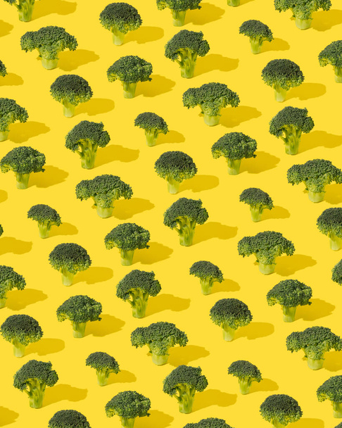 Pattern made of green broccoli flowers on a yellow background. Sustainable development minimal concept. - Photo, image