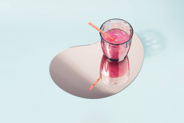 Glass of pink slime with drinking straw on a mirror. Artificial reality minimal concept. - Foto, Imagem