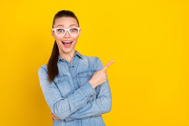 Photo portrait woman wearing glasses showing blank space amazed isolated vivid yellow color background - Fotó, kép