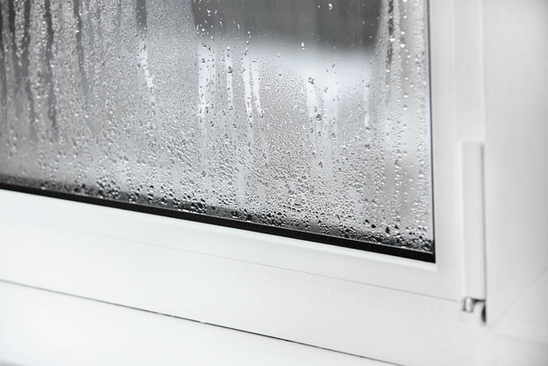 muovinen ikkuna, jossa on veden tiivistyminen lasilla. Kaksinkertainen lasi PVC-ikkuna. Konsepti: viallinen muovinen ikkuna tiivistyminen, lämpötilaero, jäähdytys, kosteus huoneessa - Valokuva, kuva