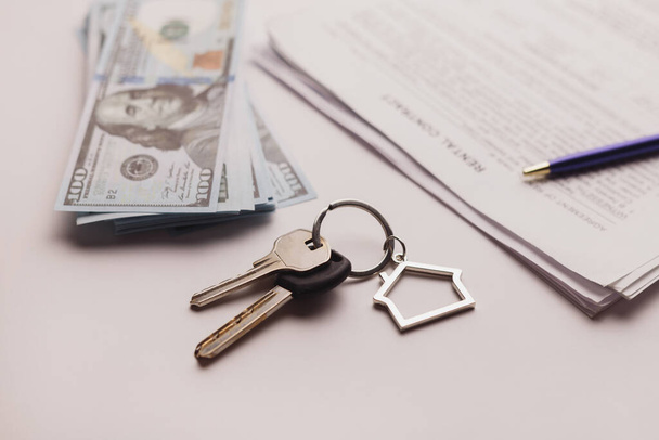 Contrato de compra de bienes raíces con dinero y llaves caseras en mesa blanca. - Foto, Imagen