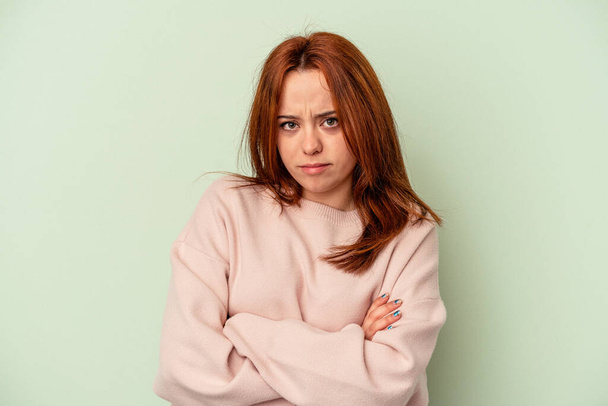 Young caucasian woman isolated on green background unhappy looking in camera with sarcastic expression. - Фото, зображення