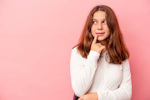 Little caucasian girl isolated on pink background looking sideways with doubtful and skeptical expression. - Fotó, kép