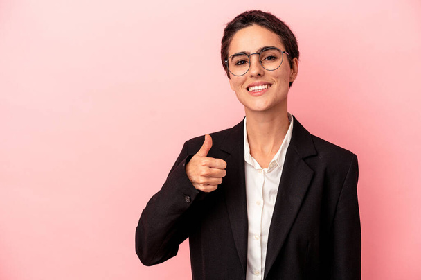 jong zakenvrouw geïsoleerd op roze achtergrond glimlachen en het verhogen van duim omhoog - Foto, afbeelding