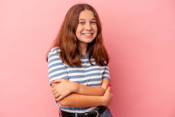 Little caucasian girl isolated on pink background who feels confident, crossing arms with determination. - Foto, Imagem