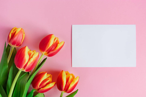 Buquê de tulipas frescas e cartão de saudação em fundo rosa. Feliz Páscoa. Conceito de férias primavera. - Foto, Imagem