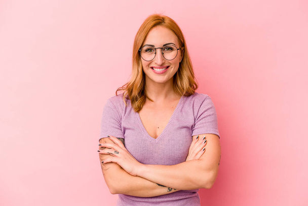 Young caucasian woman isolated on pink background who feels confident, crossing arms with determination. - Fotoğraf, Görsel
