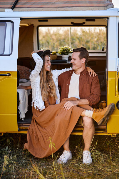 Attractive young couple sitting inside of campervan while looking outside of the van - Foto, Imagem