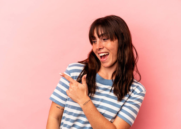 Young Argentinian woman isolated on pink background looks aside smiling, cheerful and pleasant. - Photo, Image