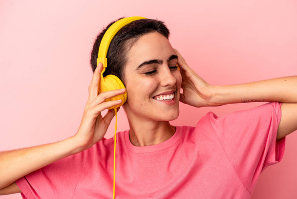 Young caucasian woman listening to music isolated on pink background - Photo, Image