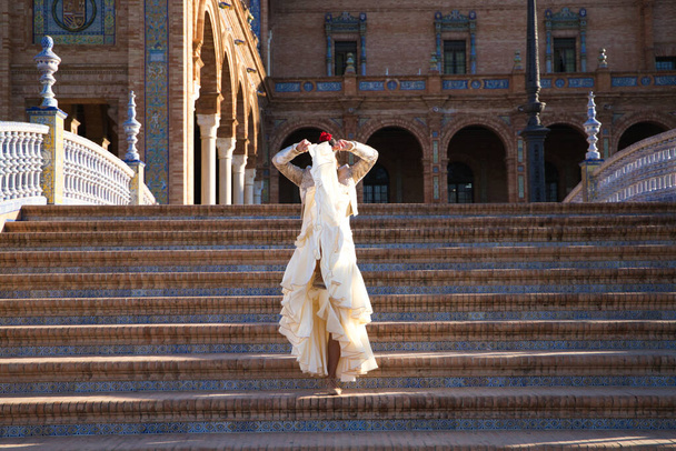 Bailarina de flamenco, mujer, morena y hermosa bailarina típica española está bailando y aplaudiendo en las escaleras de una plaza de Sevilla. Concepto flamenco de patrimonio cultural de la humanidad. - Foto, Imagen