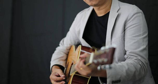 スタジオでギターを弾く男性ミュージシャンの肖像. - 写真・画像