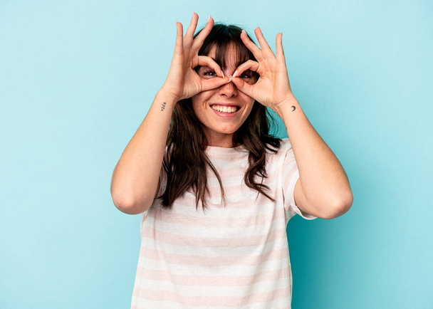 Young Argentinian woman isolated on blue background excited keeping ok gesture on eye. - Photo, Image