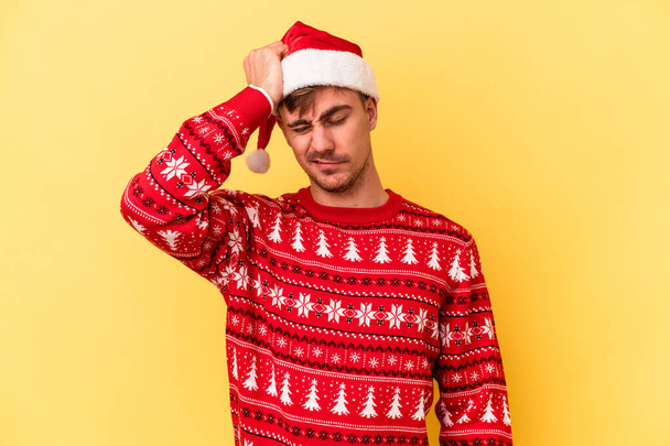 Young caucasian man celebrating Christmas isolated on yellow background being shocked, she has remembered important meeting. - Photo, Image