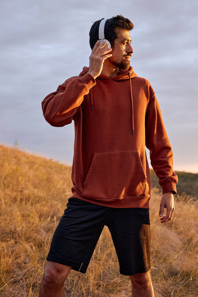 man in headphones looking at side in contemplation of landscape, listening music - Photo, image