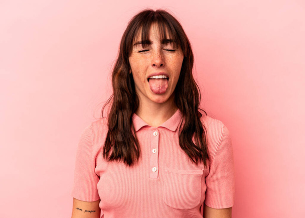 Joven argentina aislada sobre fondo rosa divertida y amigable sobresaliendo lengua. - Foto, imagen