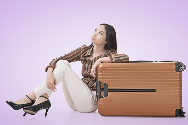 Aasialainen nainen istuu maassa matkatavaroiden kanssa
 - Valokuva, kuva