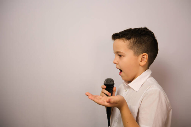 The European boy shows emotions.A boy with a microphone asserts the truth, in a white shirt.Shows truthfulness.Conveys the essence. - 写真・画像